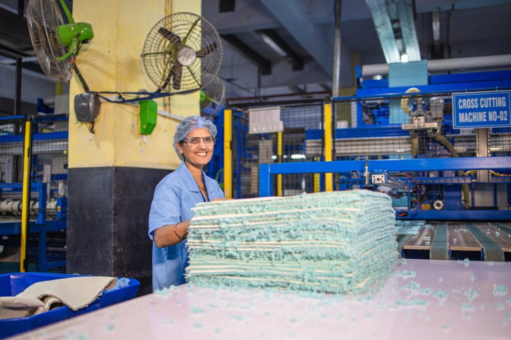 Happy female worker in textile factory smiling near cross cutting machine.