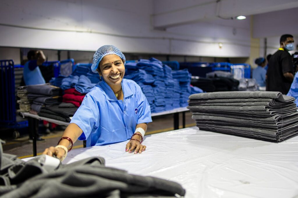 Happy female worker folding textiles in an industrial factory setting.